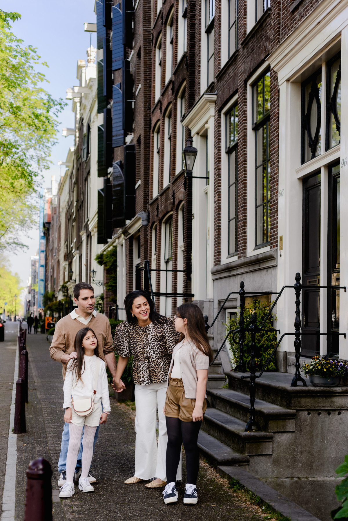 Family strolling through charming Amsterdam street, smiling together.