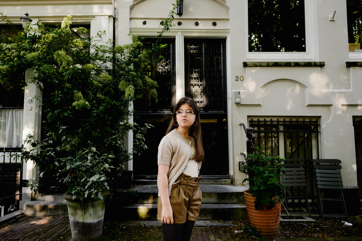 Young woman enjoying a peaceful moment in front of a historic Amsterdam home.