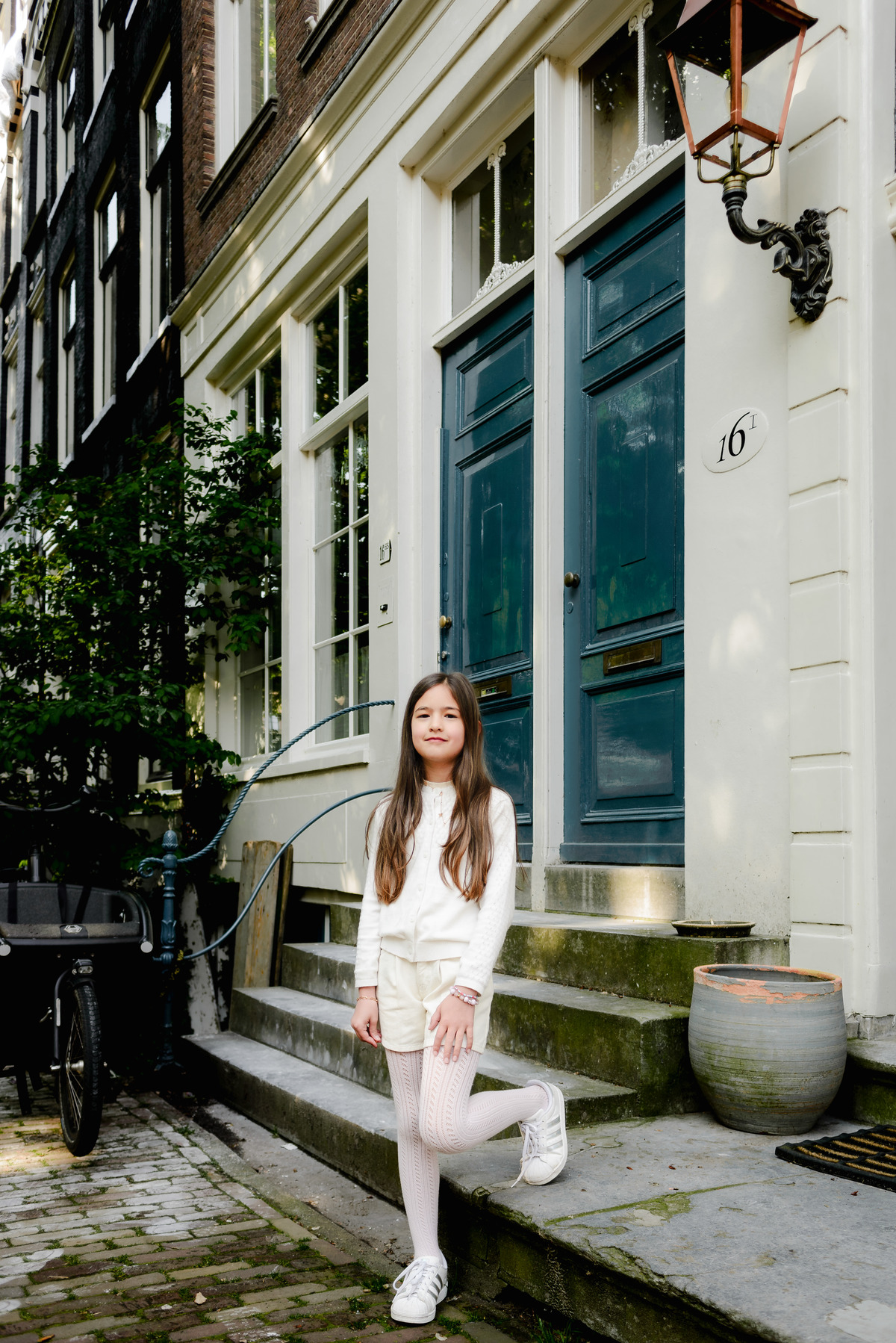 Girl posing on a quaint Amsterdam street, capturing the city’s charm.