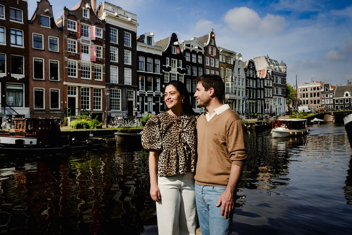 Couple on the canals of Amsterdam with historic houses as a background