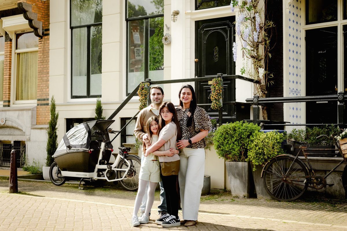Happy family posing in front of classic Amsterdam canal houses.