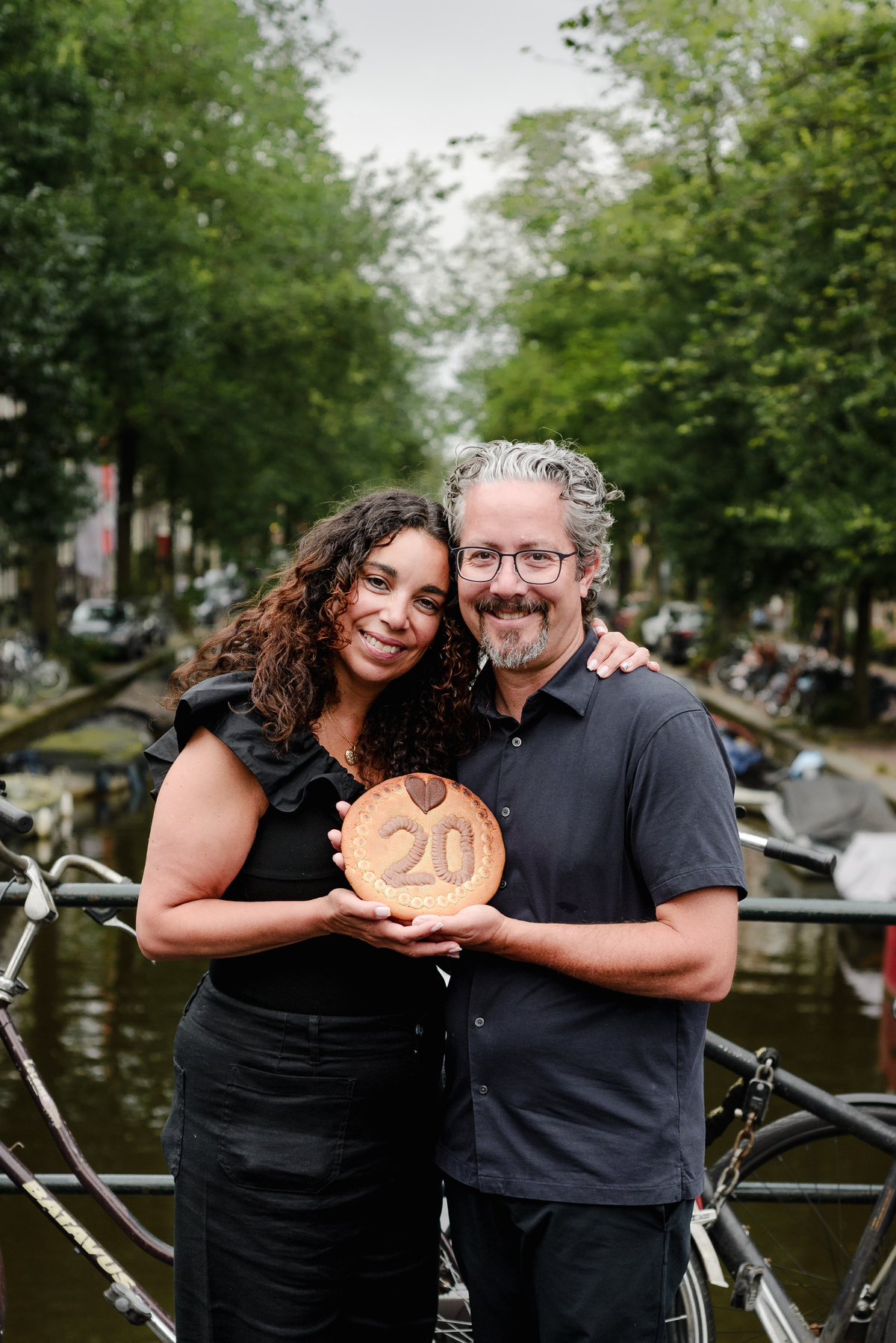 family photo session the the amsterdam canals in the Jordaan district, most famous. Family celebrating a wedding anniversary holding a famous Amsterdam cookie