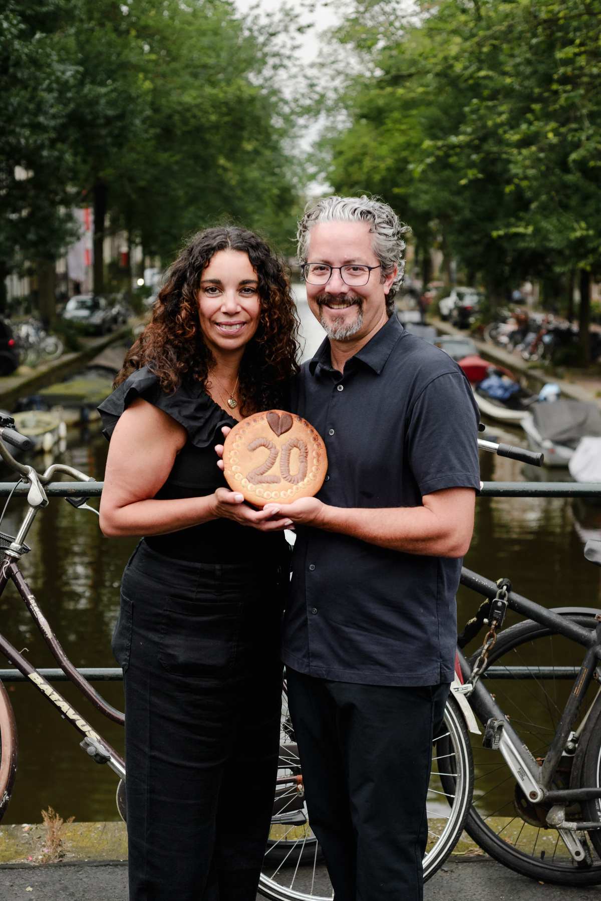 family photo session the the amsterdam canals in the Jordaan district, most famous. Family celebrating a wedding anniversary holding a famous Amsterdam cookie