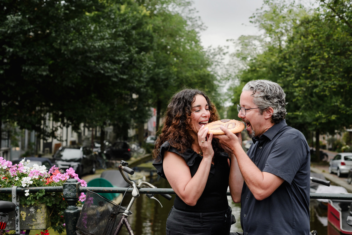 family photo session the the amsterdam canals in the Jordaan district, most famous. Family celebrating a wedding anniversary holding a famous Amsterdam cookie
