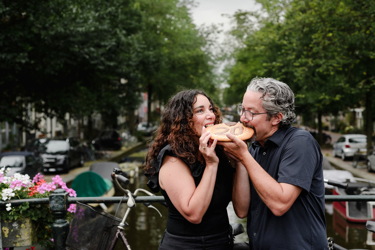 family photo session the the amsterdam canals in the Jordaan district, most famous. Family celebrating a wedding anniversary holding a famous Amsterdam cookie