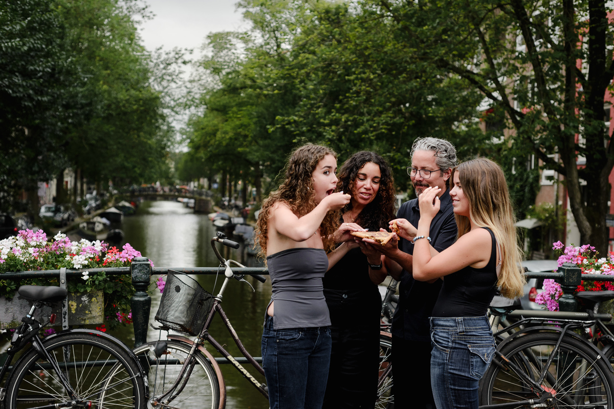 family photo session the the amsterdam canals in the Jordaan district, most famous. Family celebrating a wedding anniversary holding a famous Amsterdam cookie