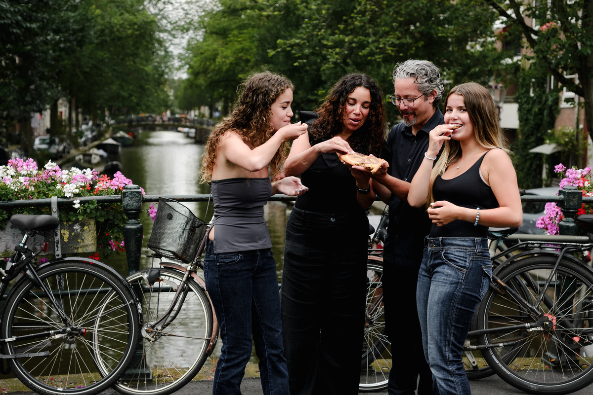 family photo session the the amsterdam canals in the Jordaan district, most famous. Family celebrating a wedding anniversary holding a famous Amsterdam cookie