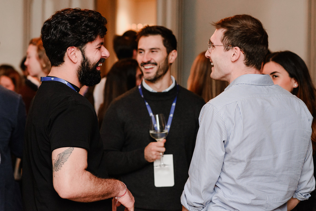 A small group of alumni laughing and networking at the IE University event, representing the casual and professional vibe of the evening.