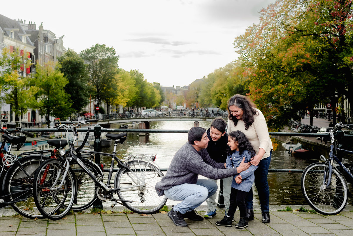 Parents playing with their two young children by the canal in Amsterdam, capturing a joyful and natural family moment during the photo session.