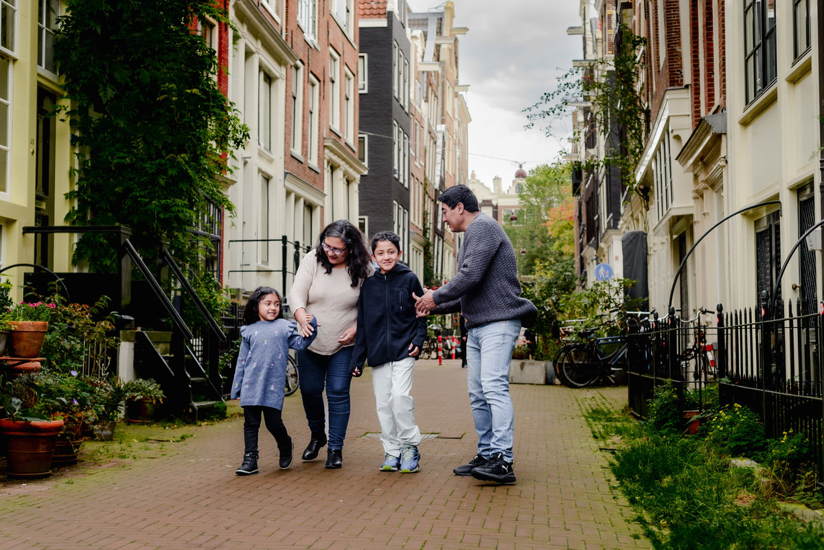 Parents playing with their two young children by the canal in Amsterdam, capturing a joyful and natural family moment during the photo session.