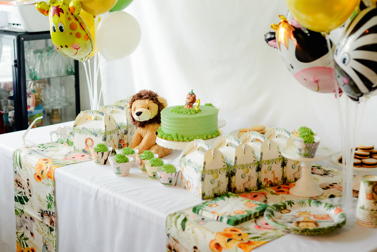 Close-up of jungle-themed decorations, featuring green and gold balloons, animal cutouts, and a colorful birthday cake.