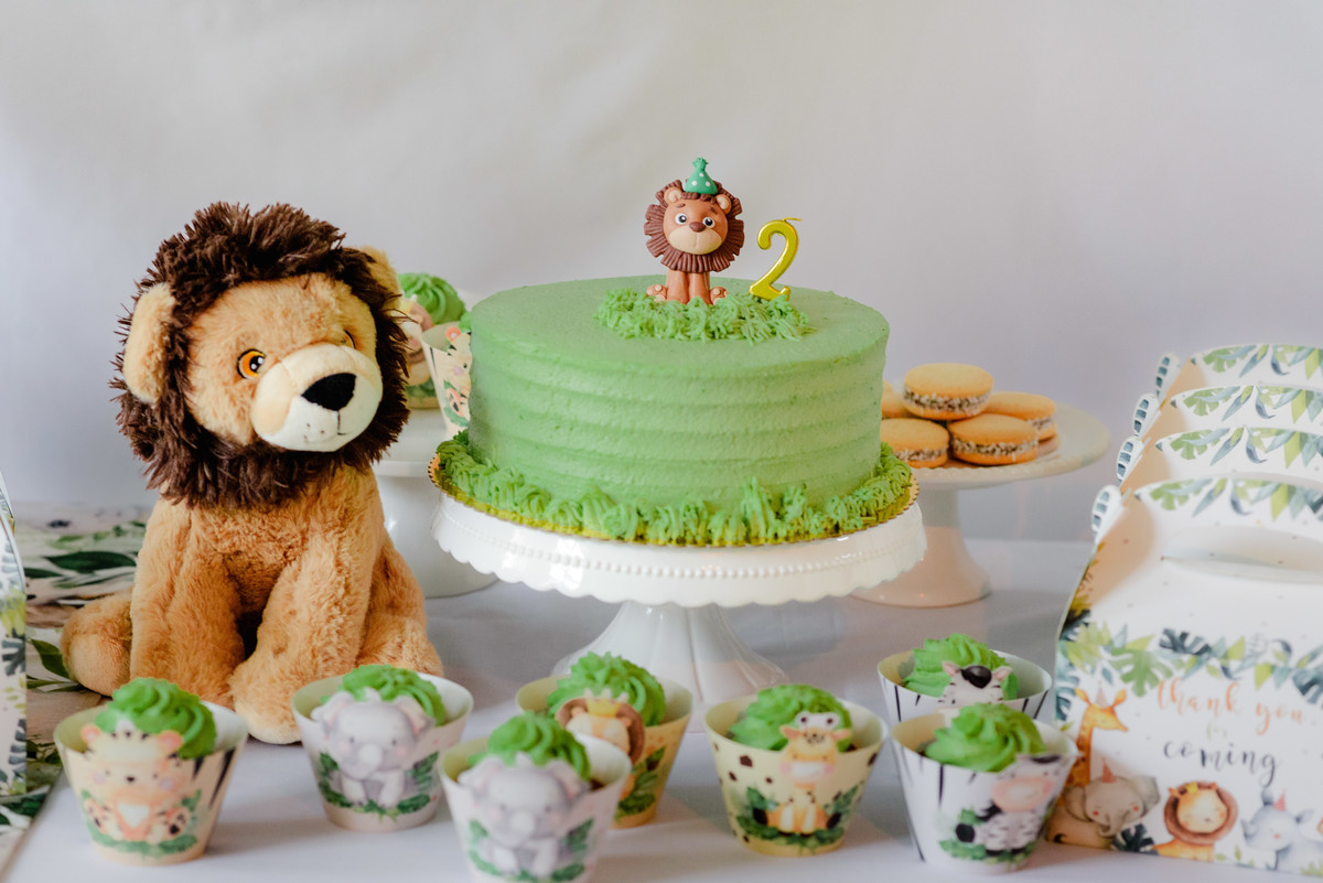 Close-up of jungle-themed decorations, featuring green and gold balloons, animal cutouts, and a colorful birthday cake.
