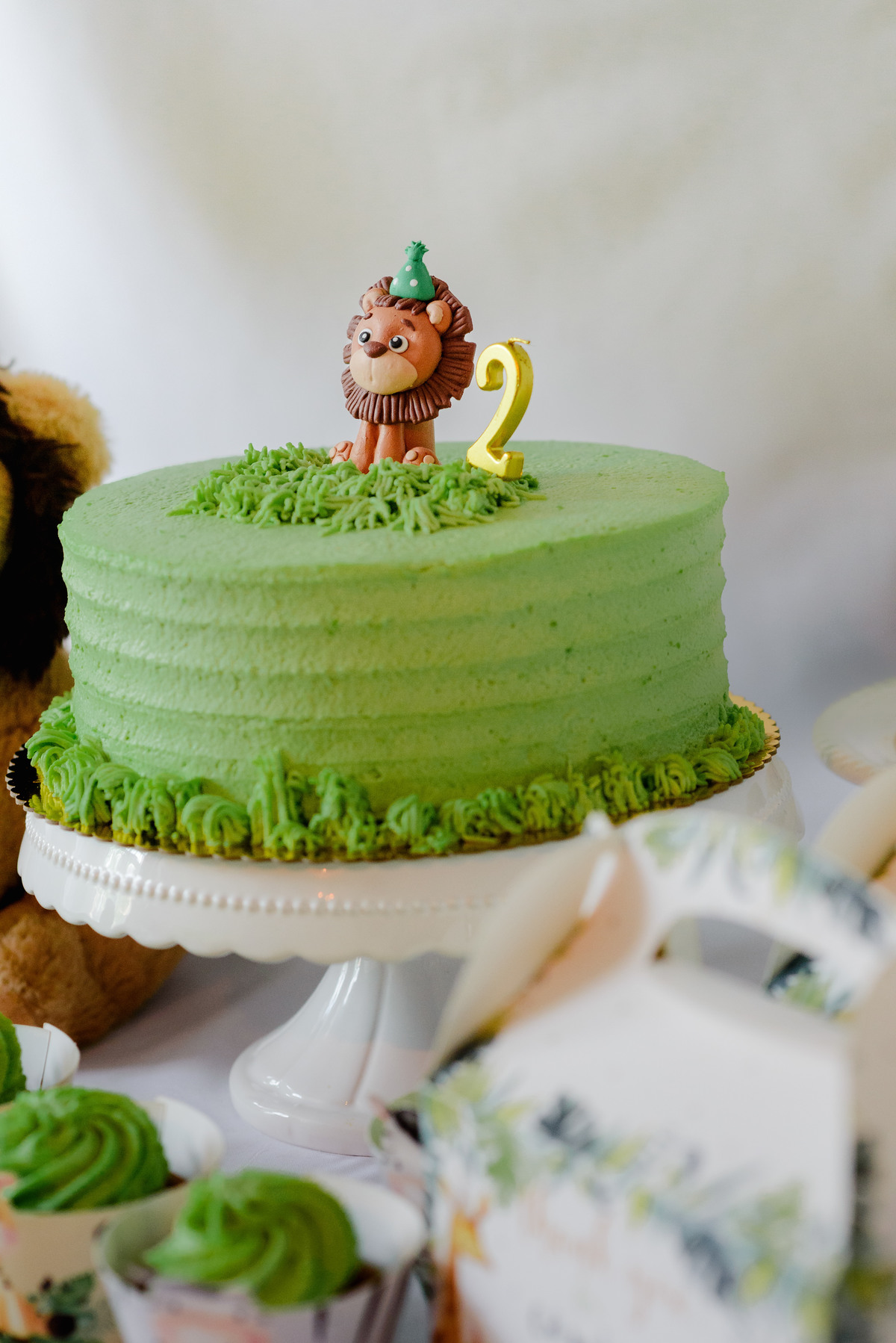 Close-up of jungle-themed decorations, featuring green and gold balloons, animal cutouts, and a colorful birthday cake.