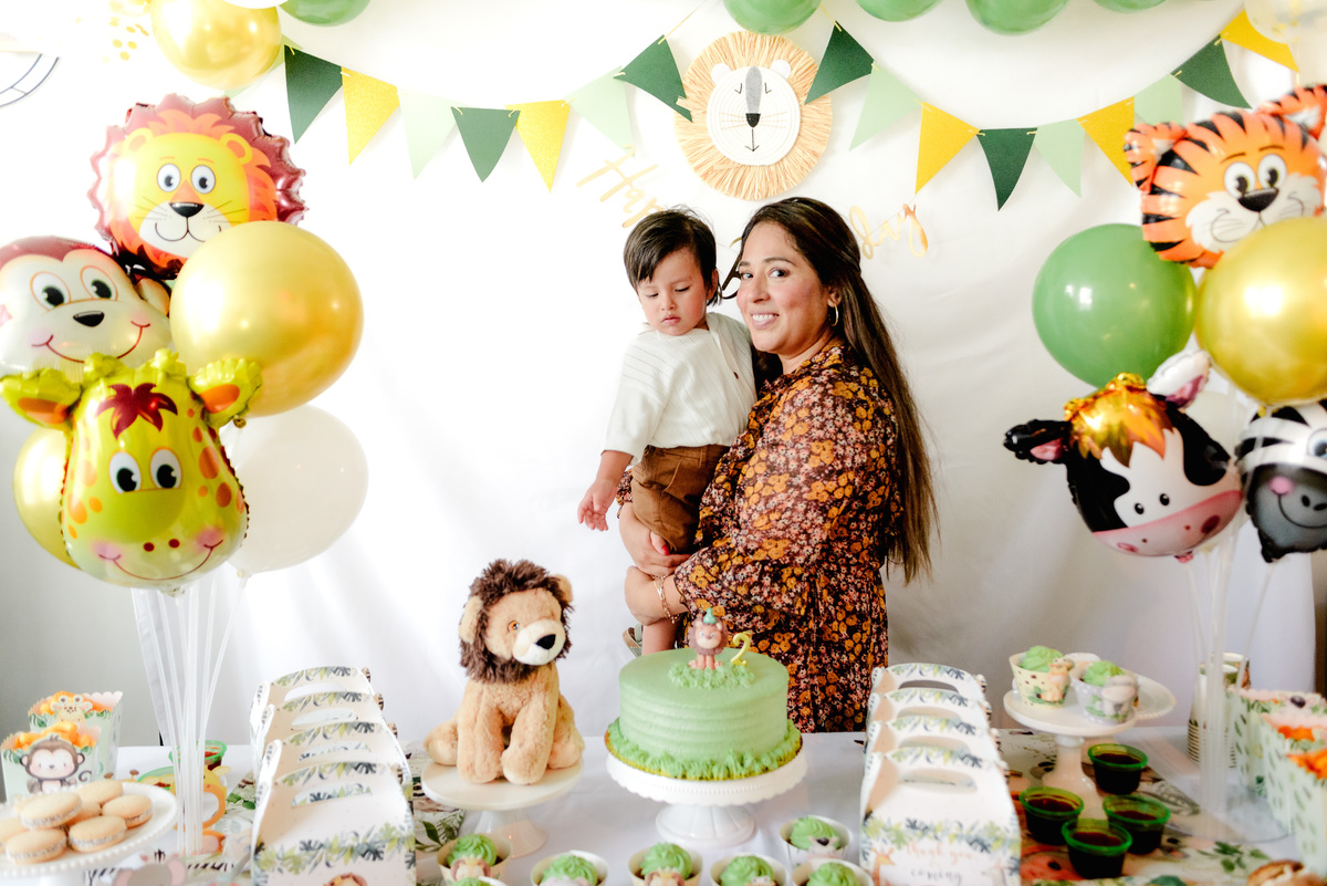 The family posing together in front of a jungle-themed photo backdrop, smiling as they celebrate the birthday boy’s special day.