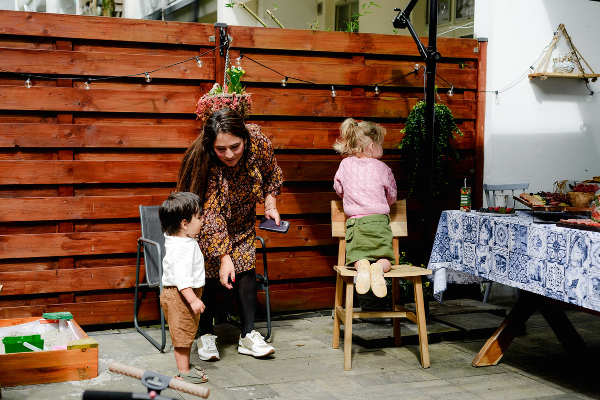 Guests enjoying a lively conversation at an outdoor table, surrounded by lush greenery and sunny weather during the birthday celebration.