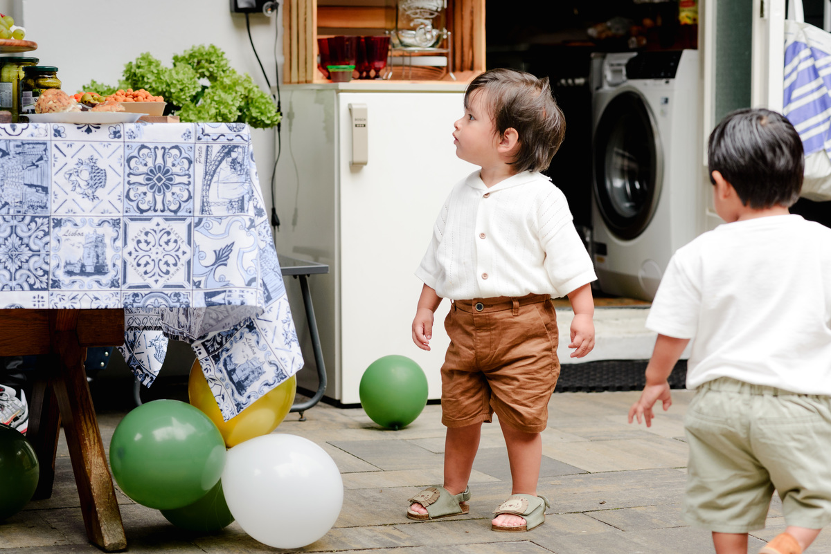 Birthday boy running joyfully in the garden, holding a small toy, with jungle-themed decorations in the background