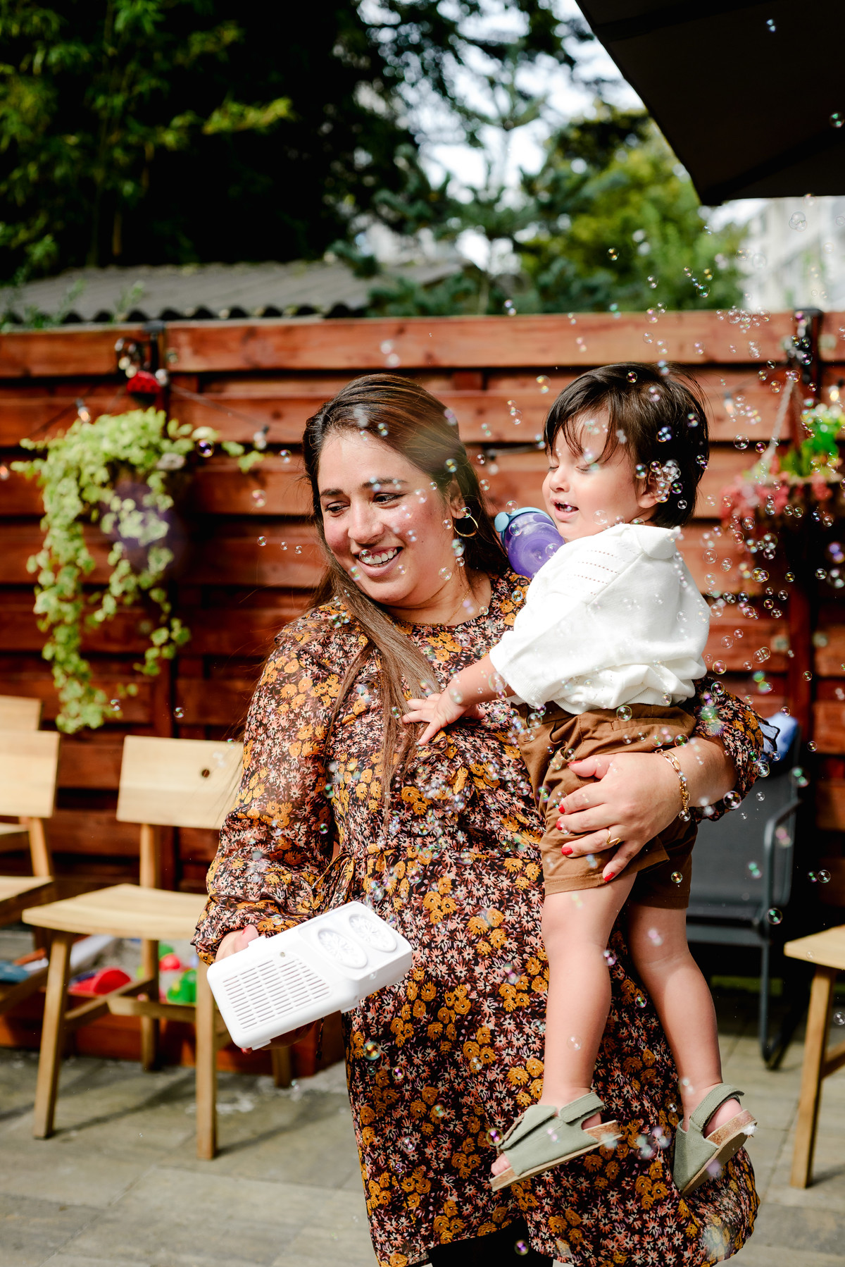 Birthday boy running joyfully in the garden, holding a small toy, with jungle-themed decorations in the background