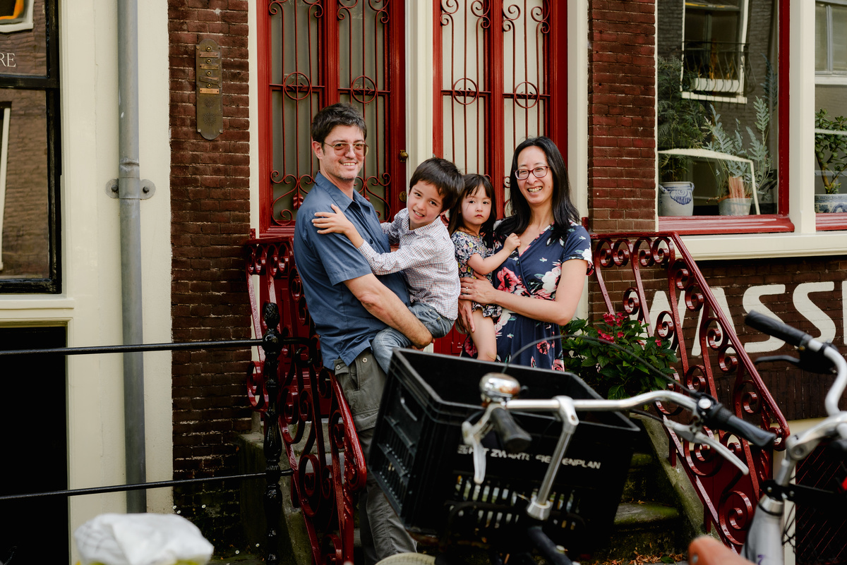 A family of four posing on a charming Amsterdam street with bikes on the foreground