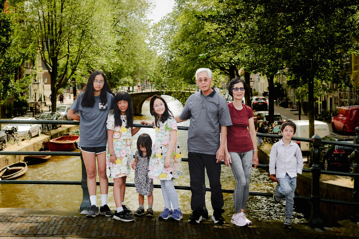 Grandparents smiling with their grandchildren in front of a picturesque canal on Reguliersgracht in Amsterdam