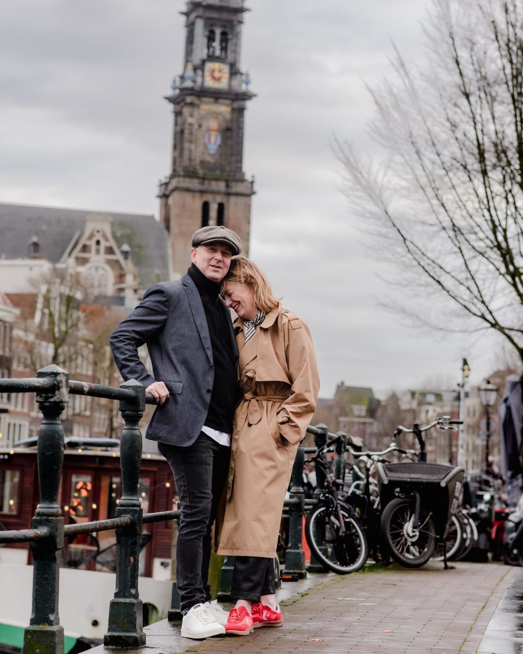 A couple shares a heartfelt moment on a canal bridge in Jordaan, Amsterdam, with the iconic Westertoren in the background. This intimate winter photo session captures the charm of Amsterdam’s historic streets and romantic scenery.