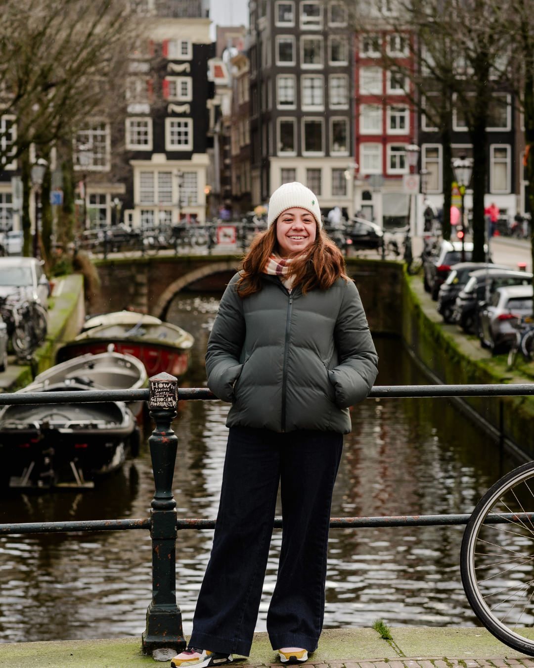 Standing by the Canal – A solo portrait of the daughter, standing confidently on a canal bridge, with Amsterdam’s signature tall, narrow houses behind her, showcasing the city’s beauty in every detail.