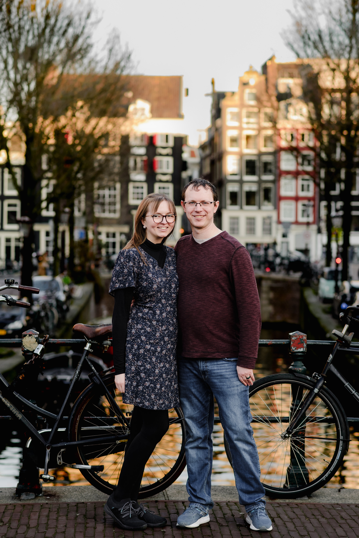 Classic couple’s portrait with bicycles and traditional canal houses in Amsterdam – a timeless backdrop for romantic photoshoots.