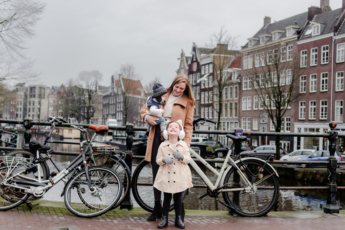 Mom and her littles by the bikes and canals — a sweet moment of laughter and love on a classic Amsterdam bridge.