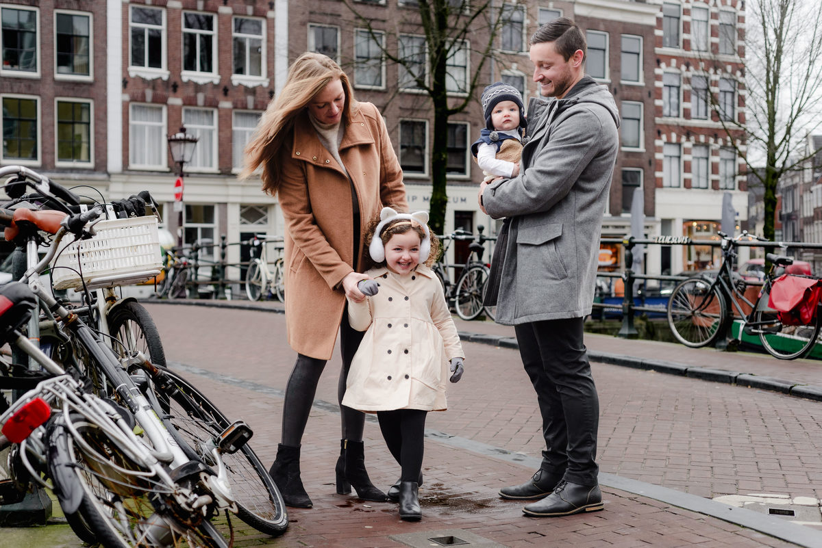 A quiet exchange of smiles as the family gathers on the bridge, bundled up and soaking in canal-side views.