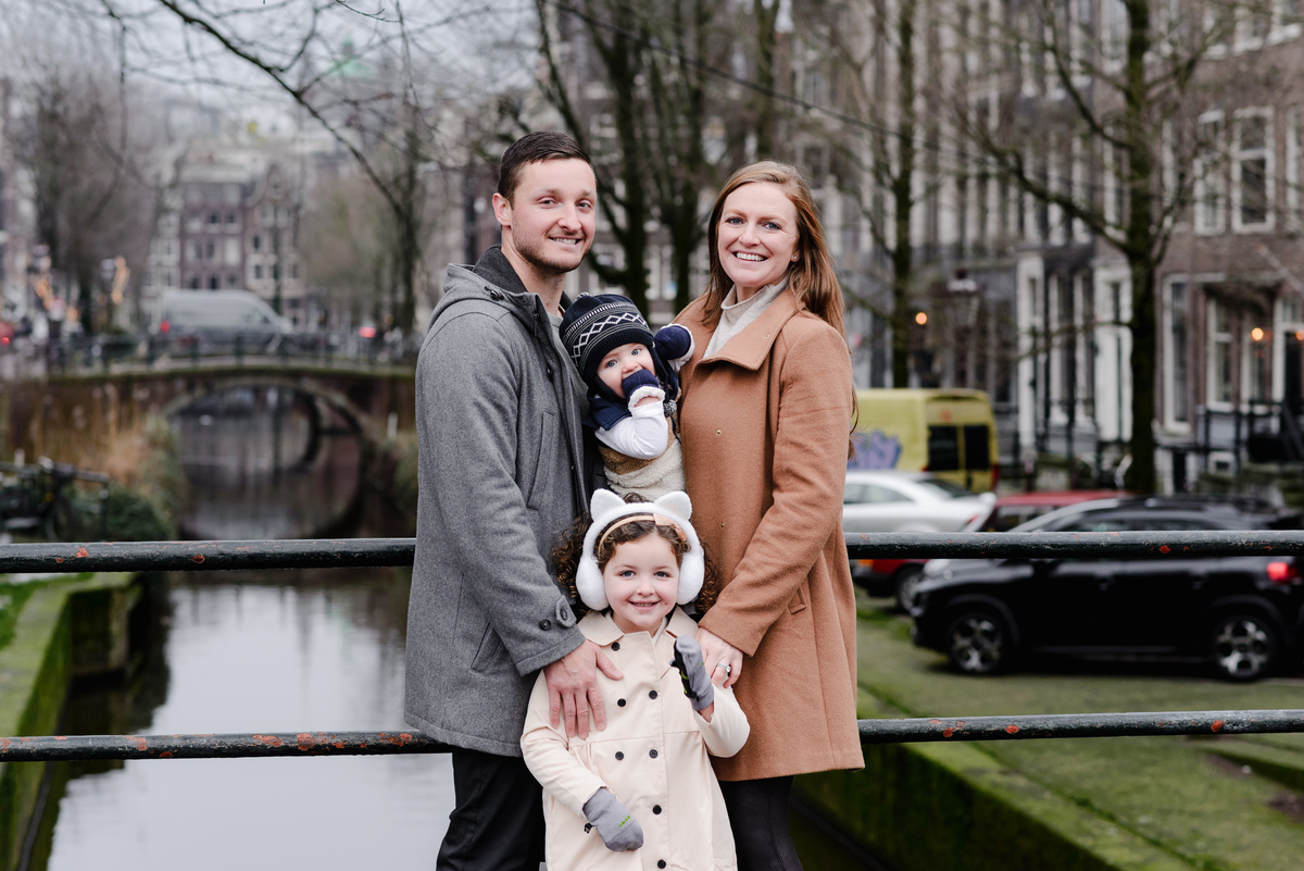 A quiet exchange of smiles as the family gathers on the bridge, bundled up and soaking in canal-side views.