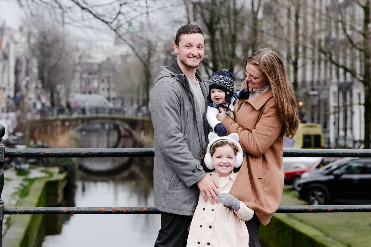 Playful family stroll down a charming Amsterdam street, swinging their daughter between them with big smiles and laughter.