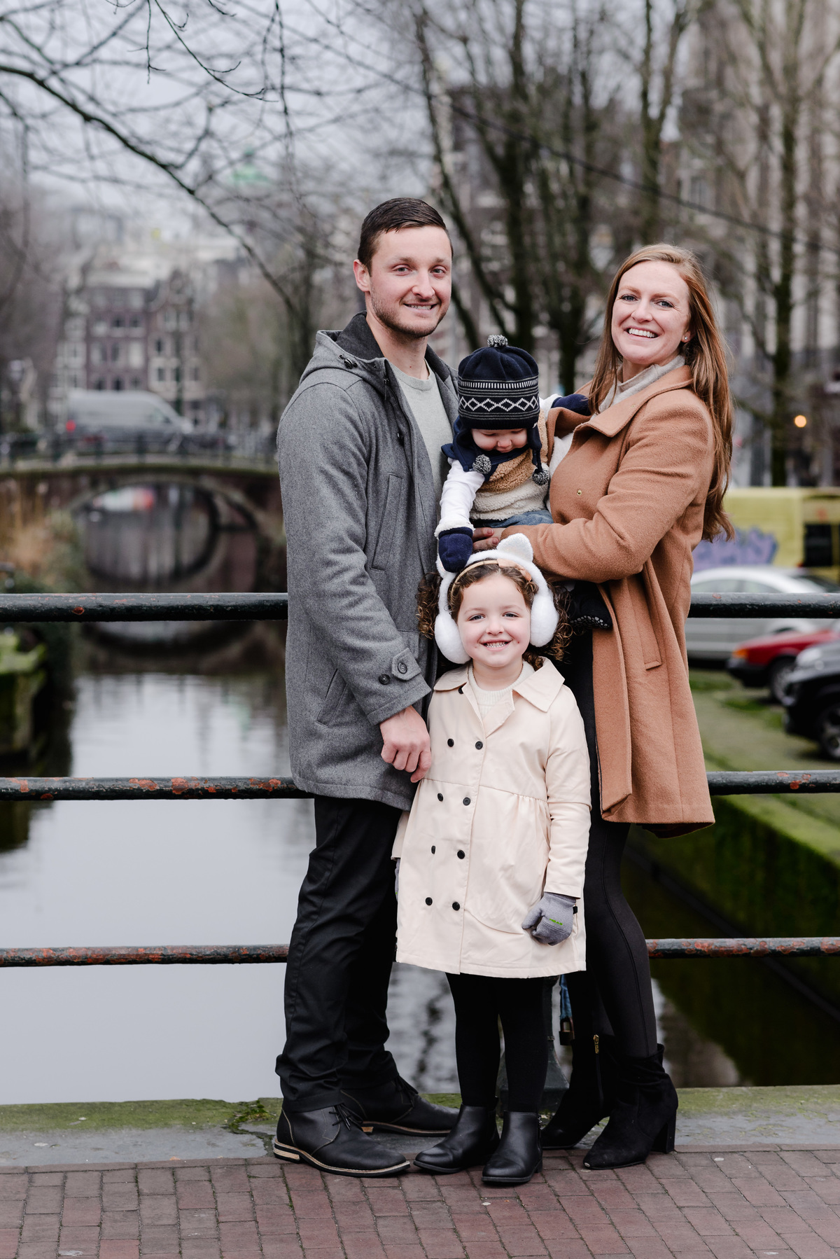 Natural, joyful walk as the family enjoys the quiet beauty of an Amsterdam neighborhood, framed by bicycles and brick façades.