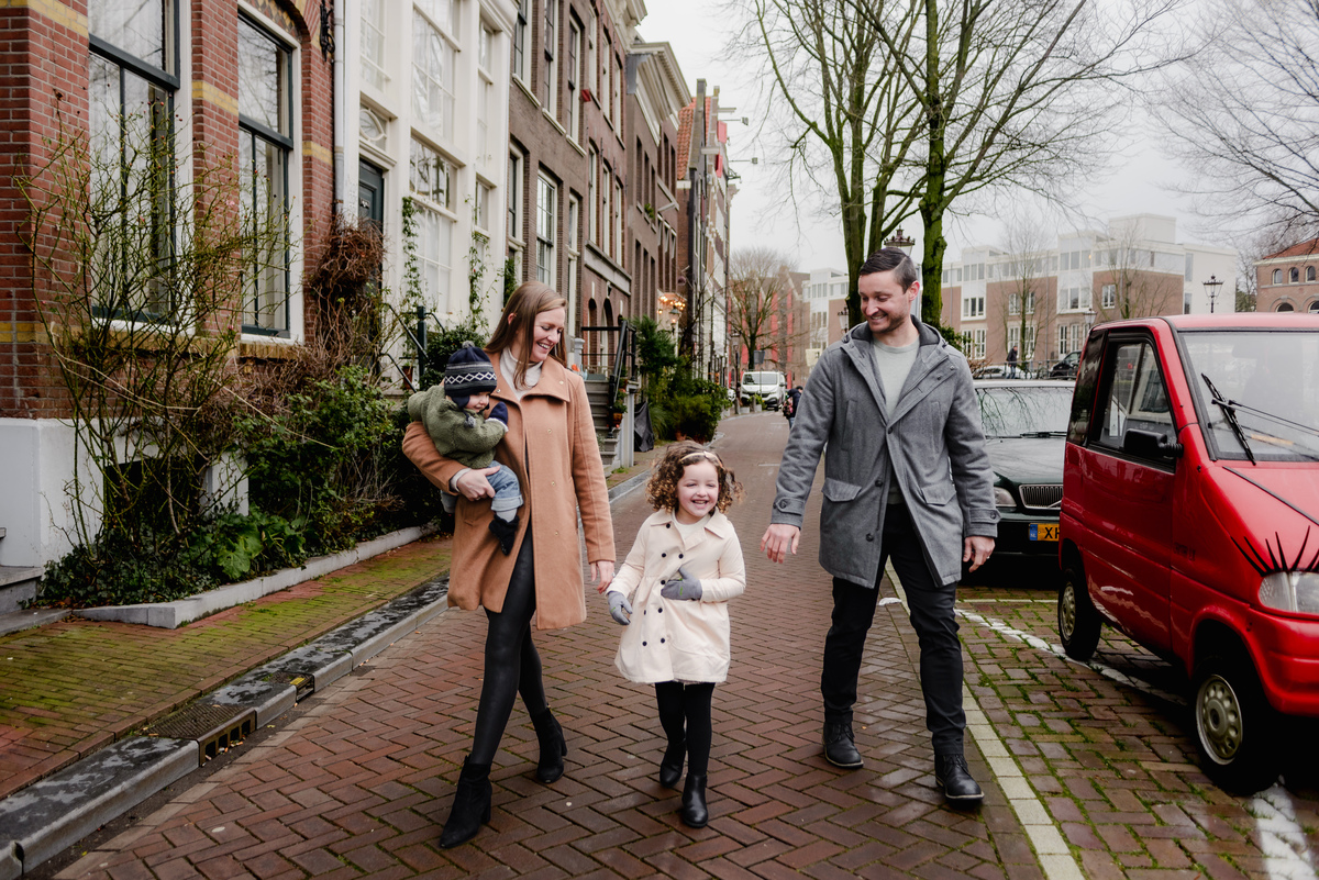 Natural, joyful walk as the family enjoys the quiet beauty of an Amsterdam neighborhood, framed by bicycles and brick façades.