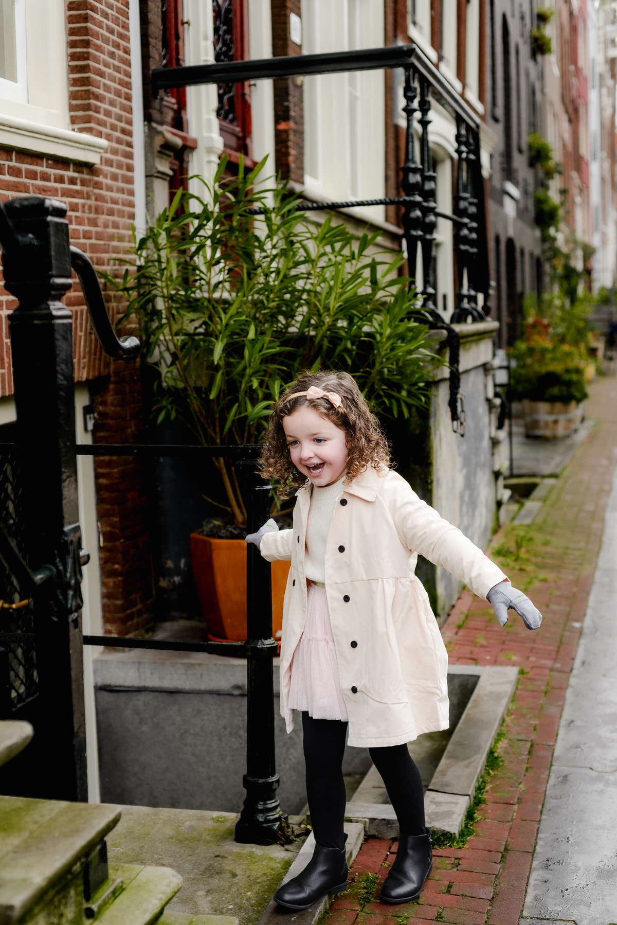 Curious and joyful, the little girl explores the steps outside a canal house, full of energy on a winter morning walk.
