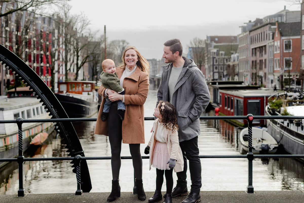Close-up of a baby in a cozy green jacket, held by mom during a winter family photo session in Amsterdam's Jordaan.