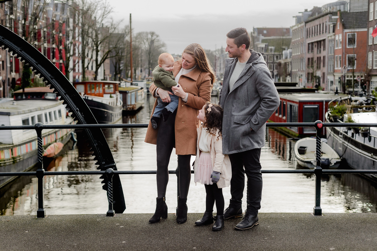 Sweet and intimate moment of a baby being kissed by mom while exploring the streets of Amsterdam during a family photoshoot.