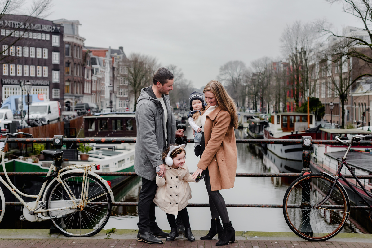 Peek-a-boo joy — little sis leans in for a giggle while the family looks on, surrounded by serene winter scenery.