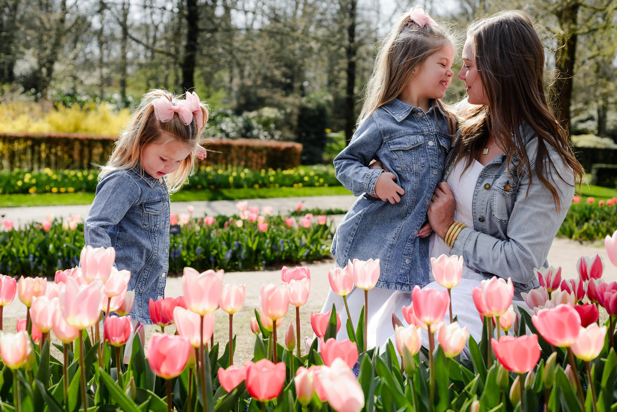 A mother shares a joyful spring moment with her daughters in Keukenhof Gardens, surrounded by blooming tulips during an early April family photography session in Holland.