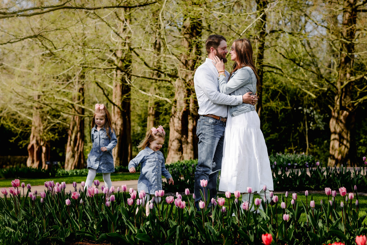 This candid springtime scene in Keukenhof Gardens features tulip blooms and a young family enjoying the season—balancing romantic connection and playful childhood moments in the heart of Holland.