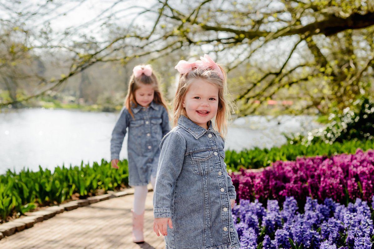 A smiling young girl explores the blooming hyacinth beds by the lake in Keukenhof Gardens, capturing the joy of spring in the Netherlands during an early April family photoshoot.