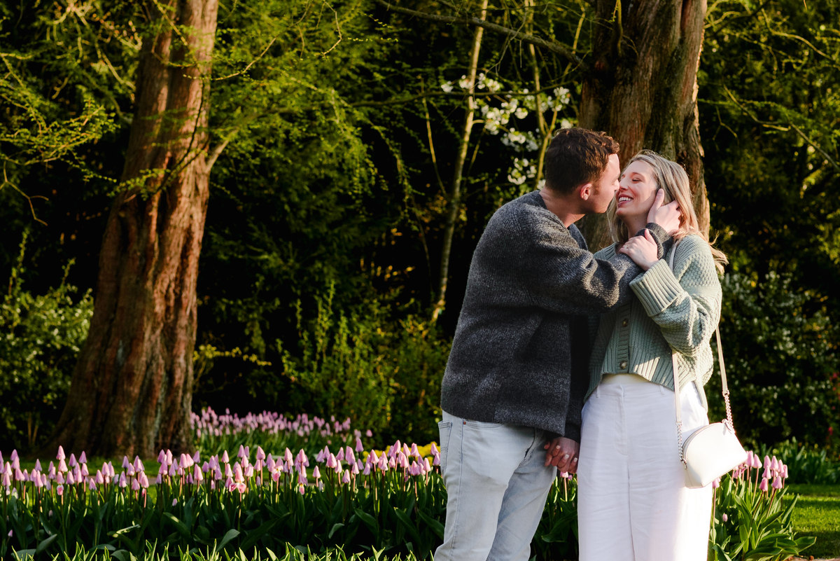 Engaged couple kisses in front of a blooming tulip garden, soaking in their special moment at Keukenhof Gardens.