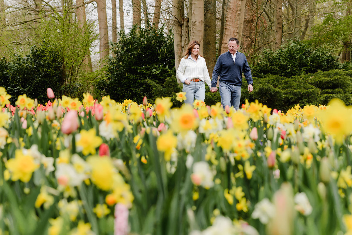 A cheerful walk through a golden-yellow field of daffodils and tulips, the couple shares a quiet, joyful moment in nature.