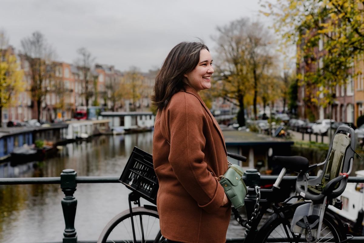 Side profile of a woman laughing near parked bicycles on a bridge in Amsterdam, during a 15-minute photo session.