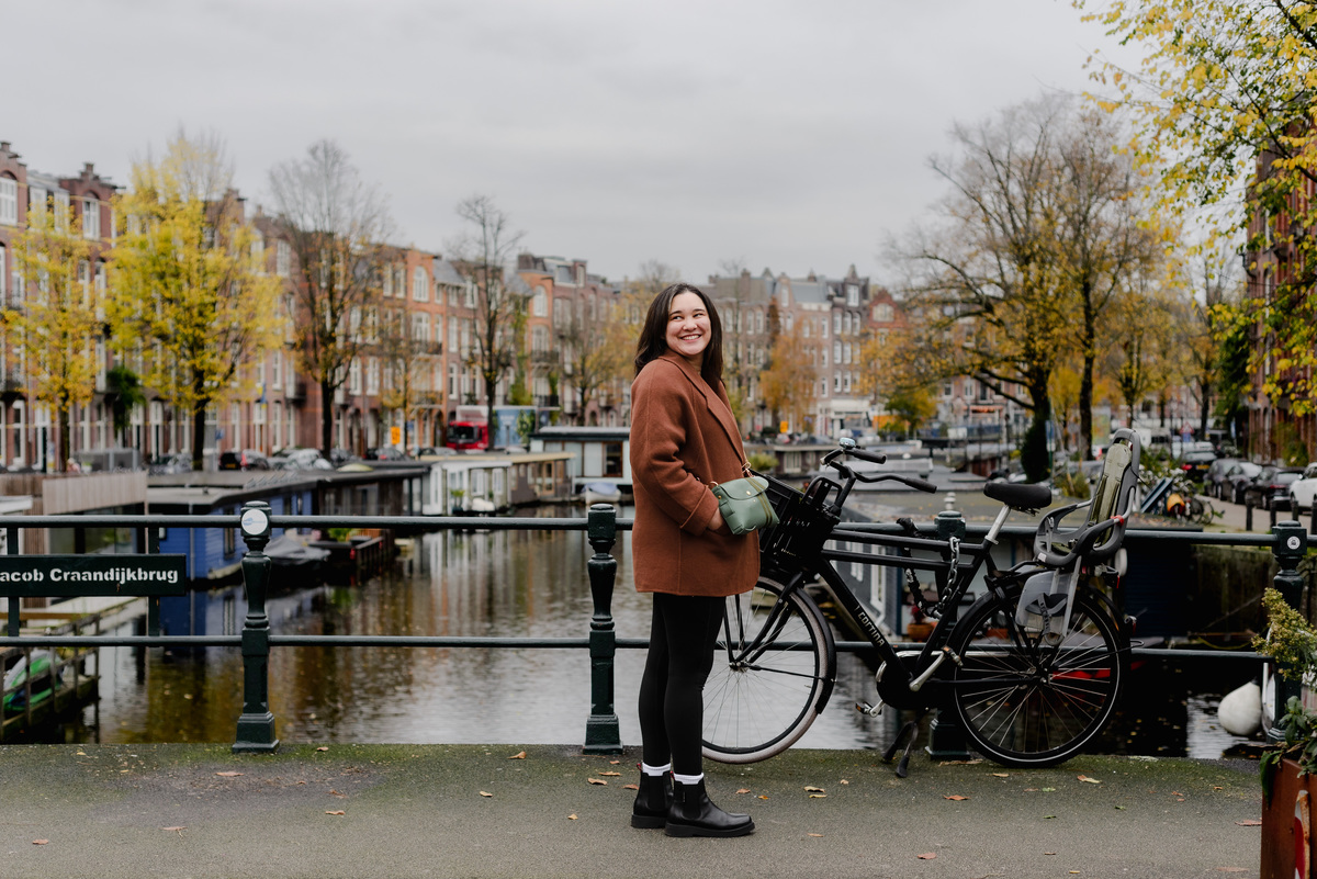 Woman enjoying a moment on the Jacob Craandijkbrug bridge, with a green crossbody purse and a relaxed autumn vibe.