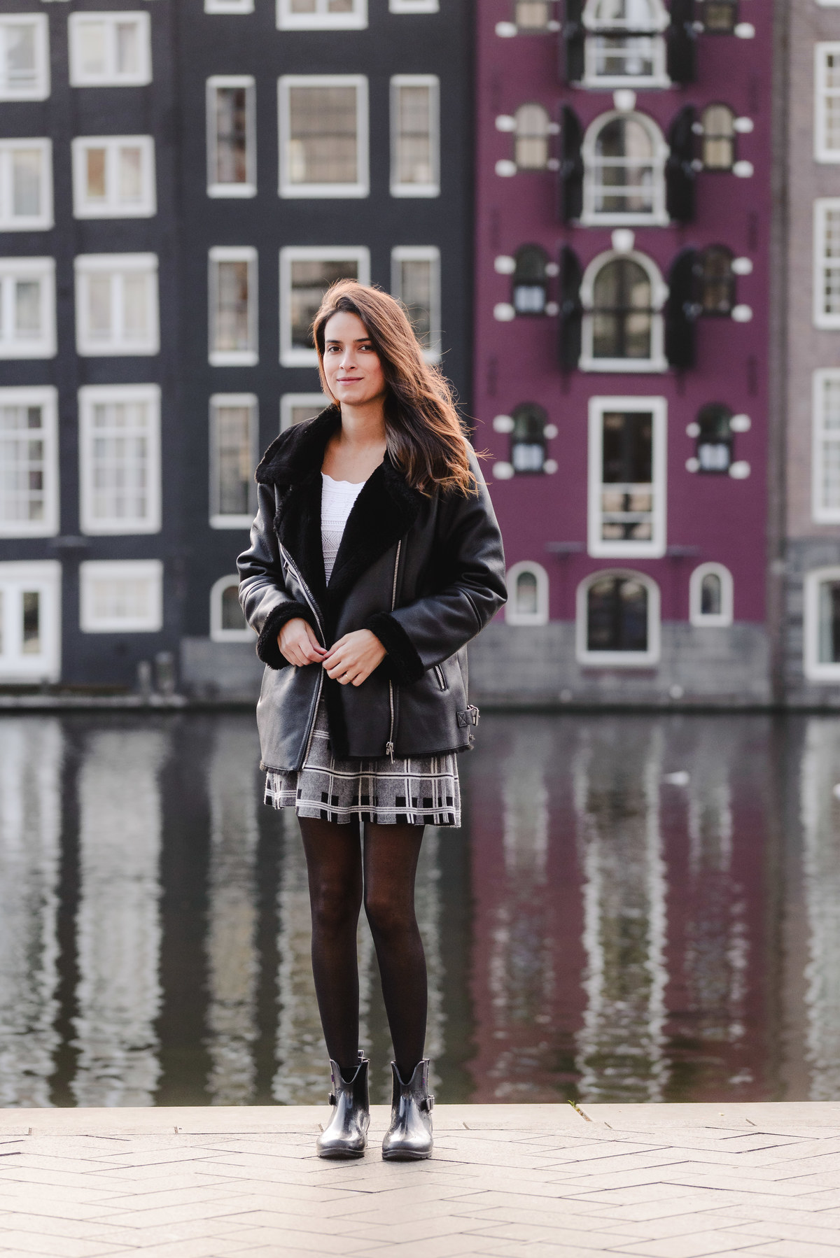 Travel portrait of a woman in front of Amsterdam’s iconic dancing houses near Damrak during a solo photography session