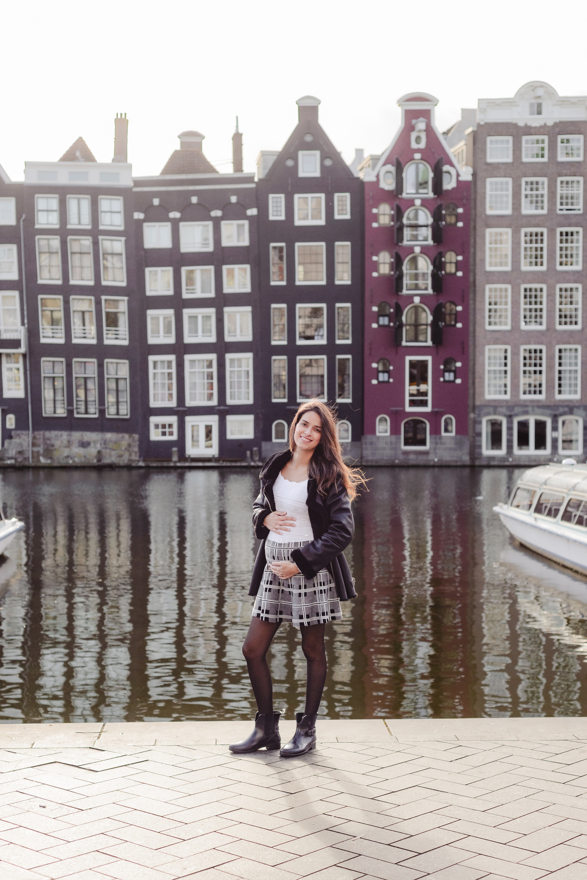 Traveler smiling during her Explorer photo session at Damrak, with Amsterdam’s well-known canal houses behind her