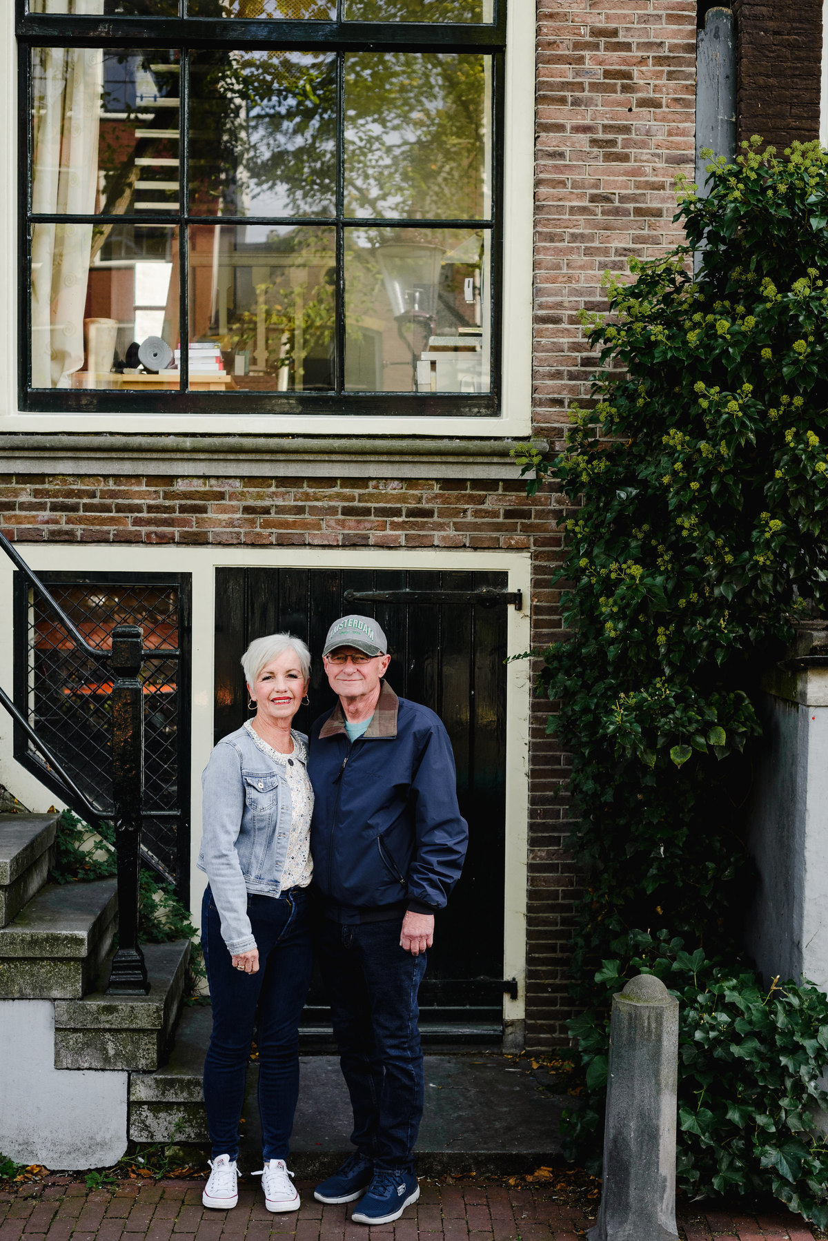 Couple standing together in front of a historic Amsterdam canal house doorway during a 25th anniversary photo session.