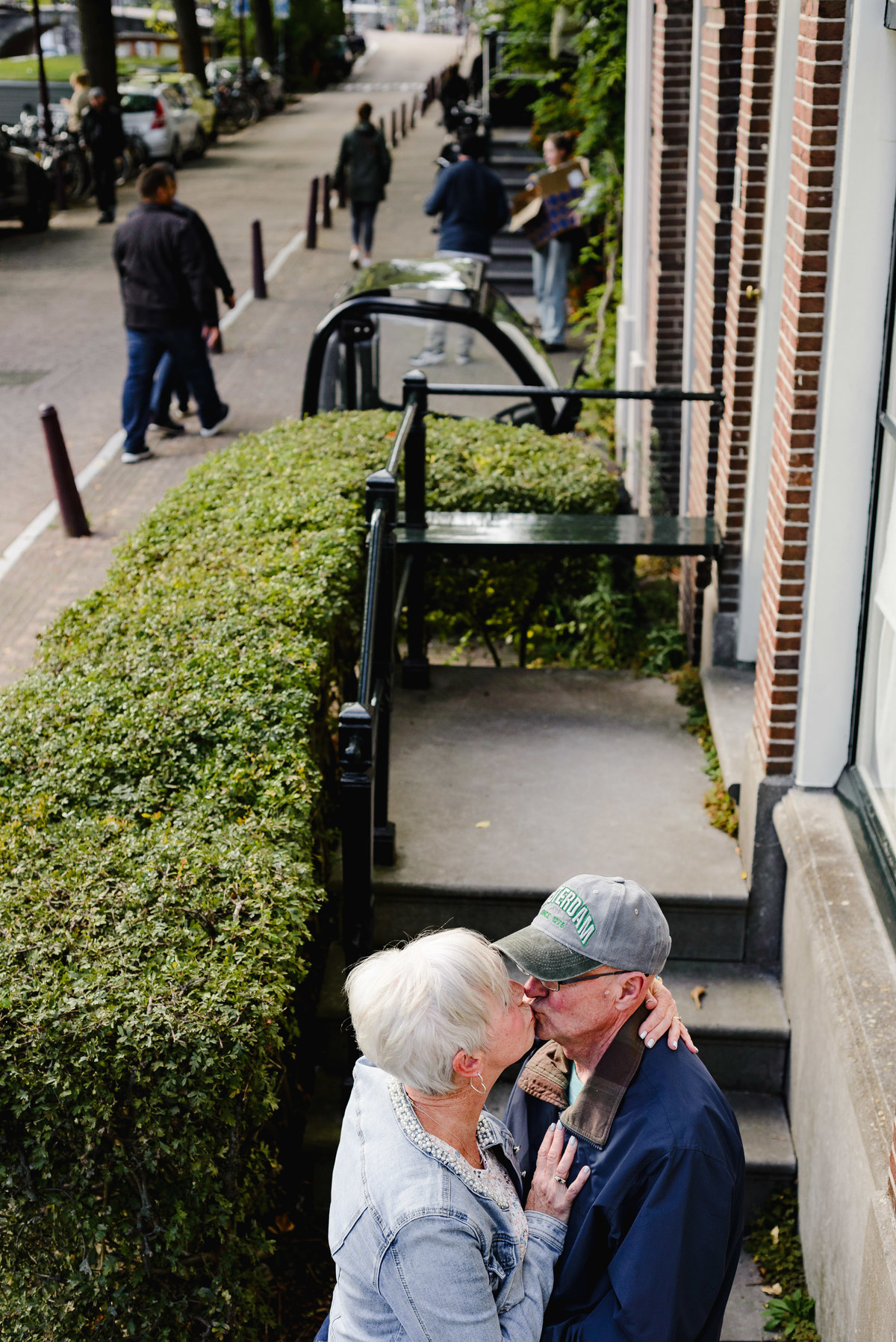 Intimate moment of an anniversary couple kissing near a residential entrance in Amsterdam, photographed from above along a quiet street.