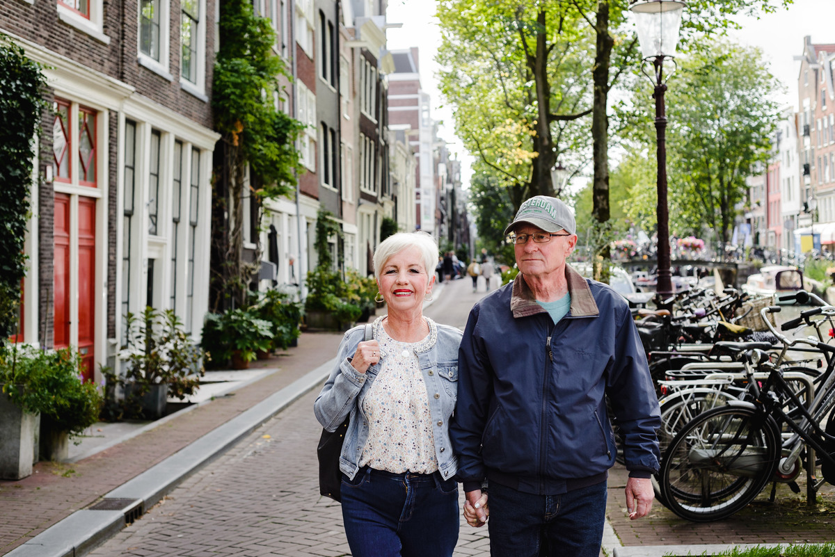 Couple walking side by side along an Amsterdam canal street, capturing a relaxed and natural anniversary moment.