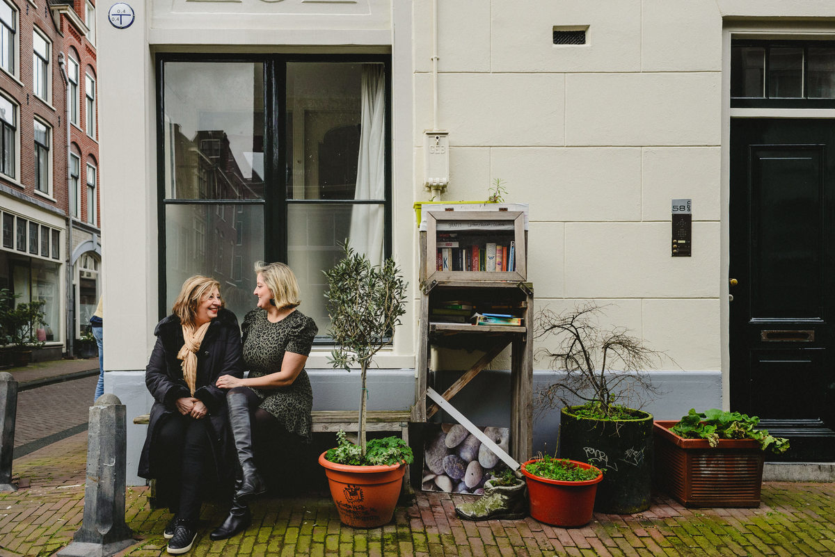 Mother and adult daughter sitting together on a bench in Amsterdam, sharing a quiet moment during a family photo session.