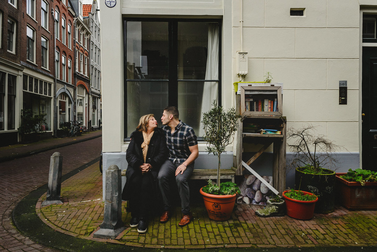 Mother and adult son leaning close together on a bench in Amsterdam, photographed during a birthday family session.